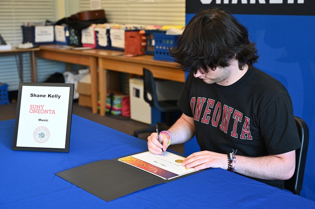 A student signs to study music at SUNY Oneonta.