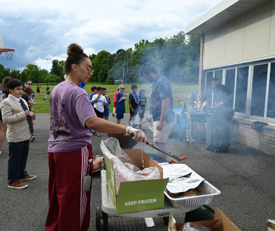 Teachers grill burgers and hot dogs for fifth graders