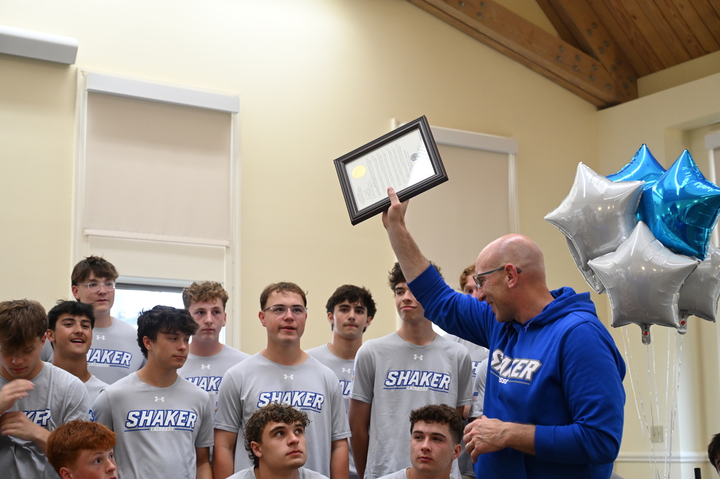Coach Hennessey lifts the proclamation above his head as players look on.