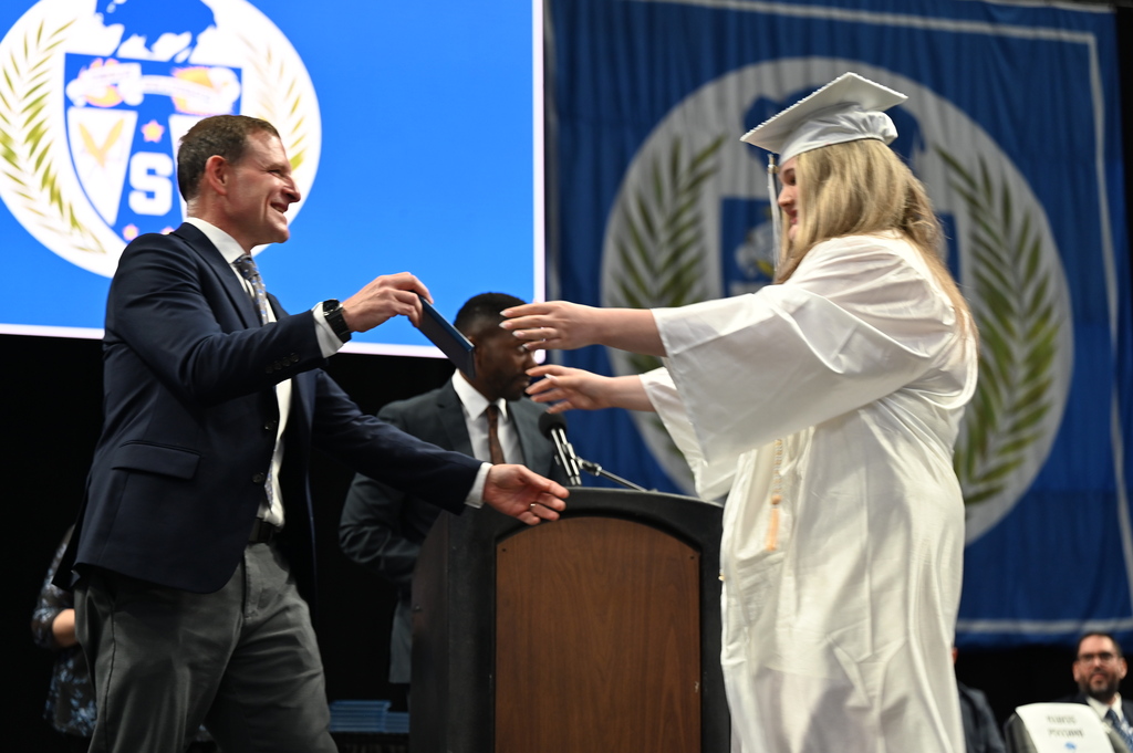 Graduate receives diploma and moves to hug dad