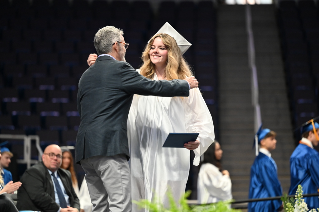 Graduate hugs dad and receives diploma