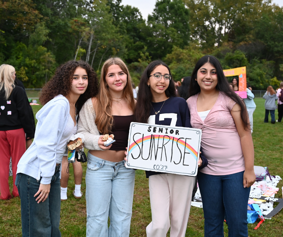 Seniors in front of the sunrise holding up a sign