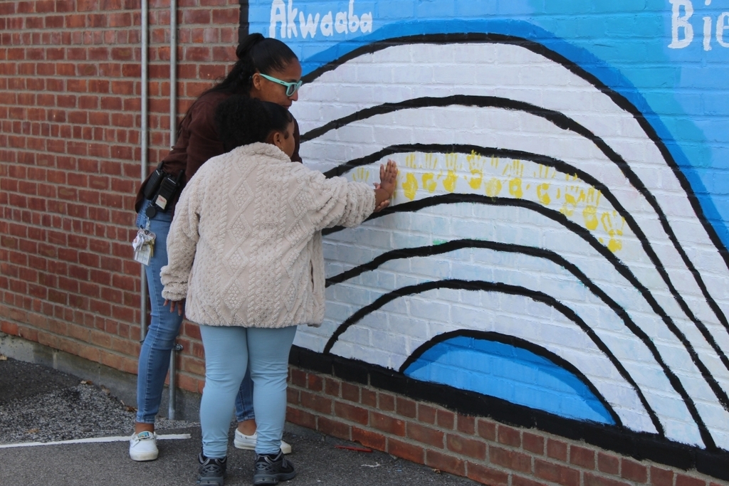 student placing their hand on the wall with the help of a teacher