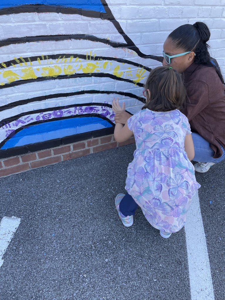 student placing their hand on the wall with the help of a teacher