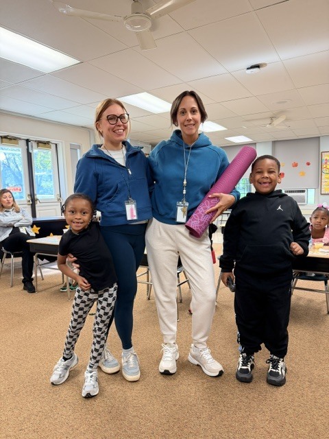 students posing with two teachers and a yoga mat