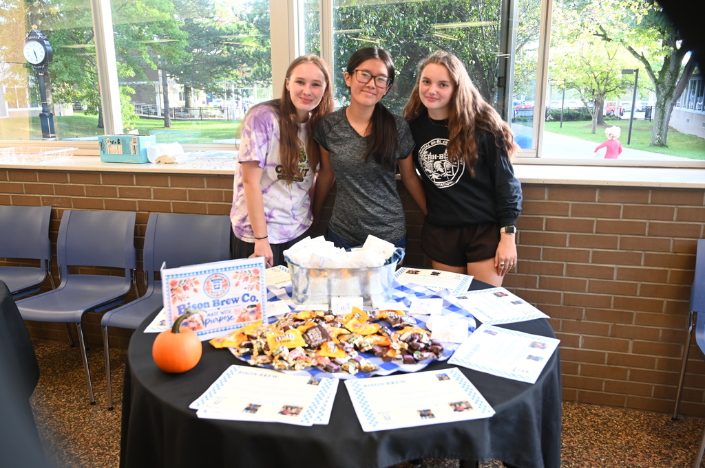 three students standing in front of the bison brew food display