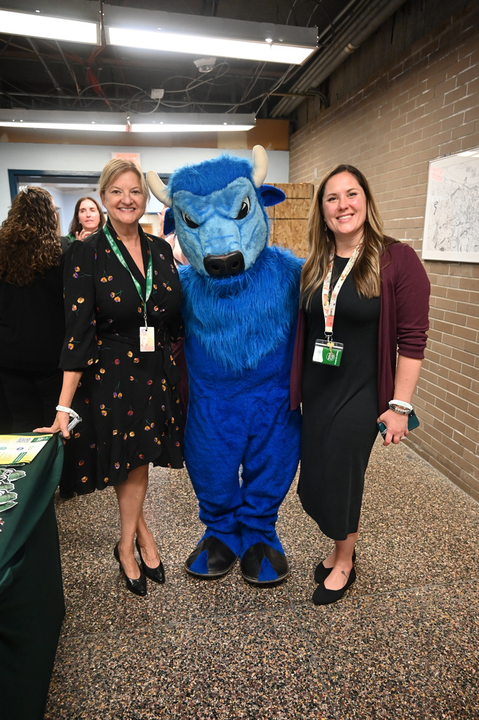 two females standing and posing with the bison