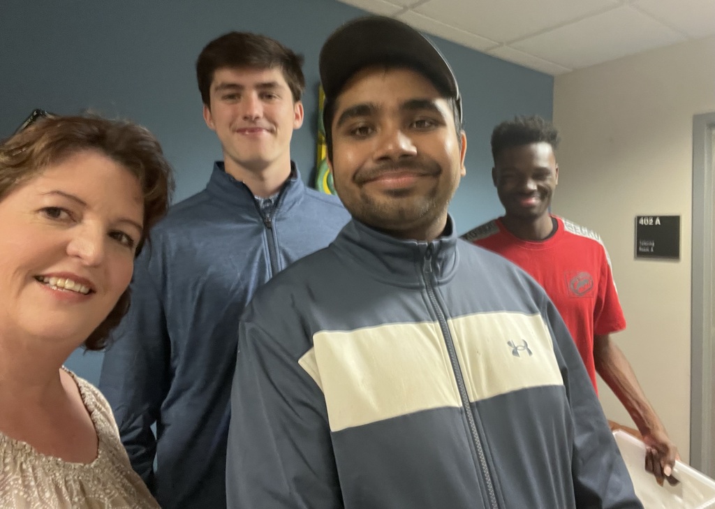An image of four people standing together in a hallway, smiling.