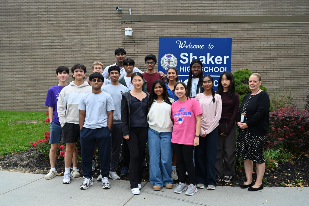 A group of students honored as Commended Students for the 2027 National Merit Scholarship Program, pose with their principal, Mrs. Fox, in front of the Shaker High School sign.