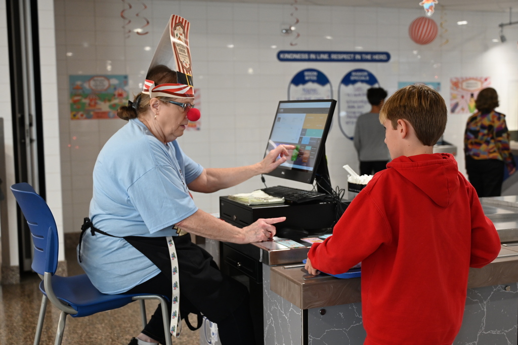 Shaker Middle School Cafeteria worker wearing clown noses and circus hats cashing out a students for lunch