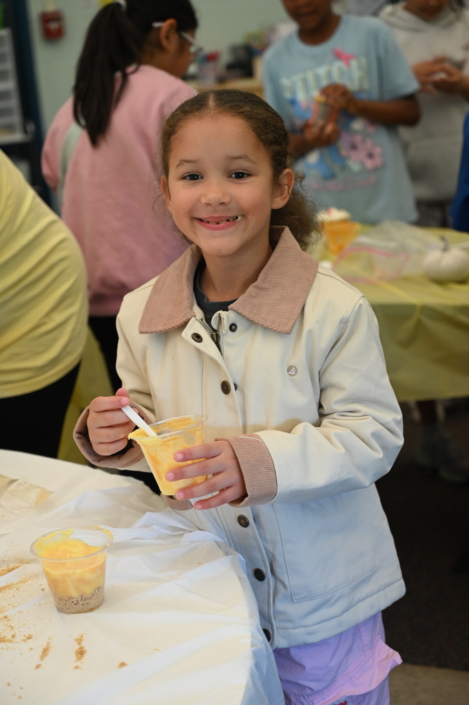 student smiling at the camera after trying pudding