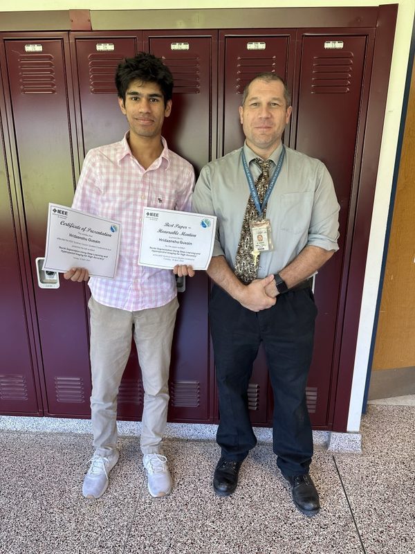 Hridaanshu Gusain poses with his teacher and his certificates from a prestigious IEEE Conference.