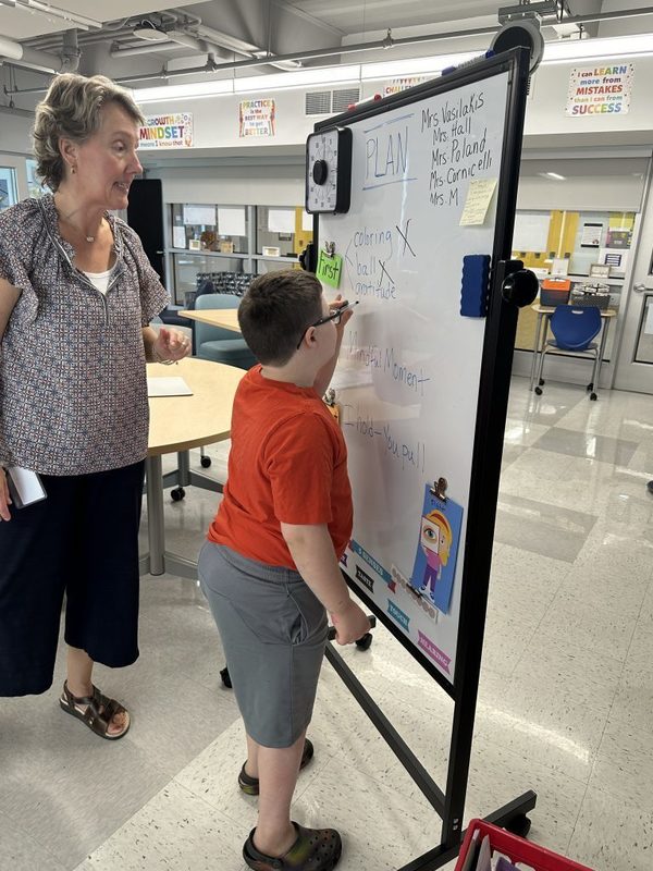 Mrs. Michelle Vasilaskis looks on as one of her students write at the whiteboard.