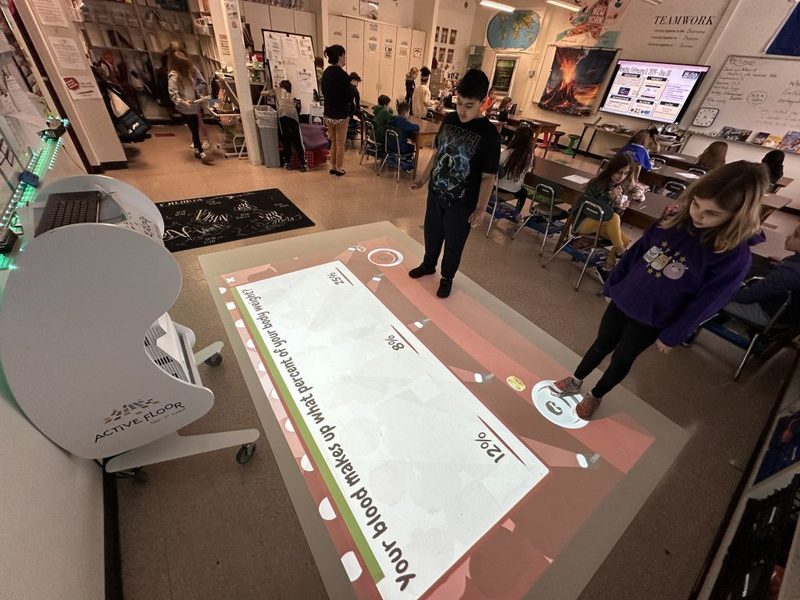 Two students compete in an educational game using the “Active Floor.”