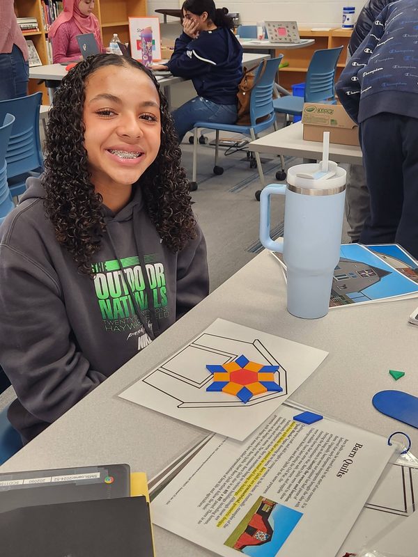 A student works on a barn quilt creation as part of a lesson on math transformations.