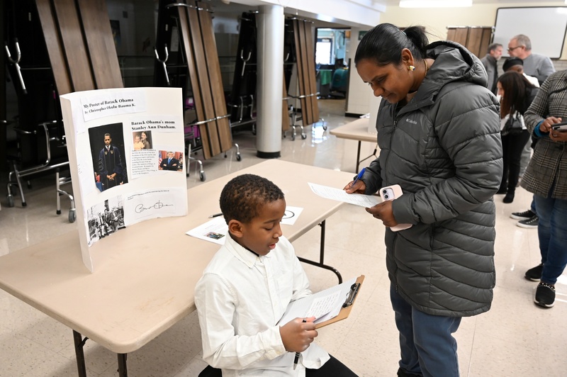 A student presents his project on former president Barack Obama to a visiting parent at school.