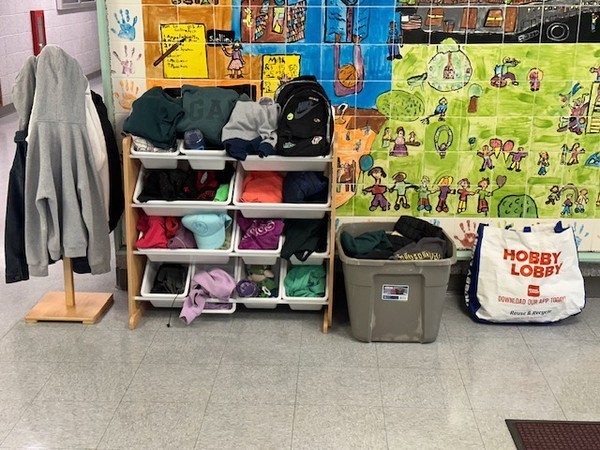 A room with a floor, a storage unit with organized clothing, and a bag with the text "HOBBY LOBBY" on it.
