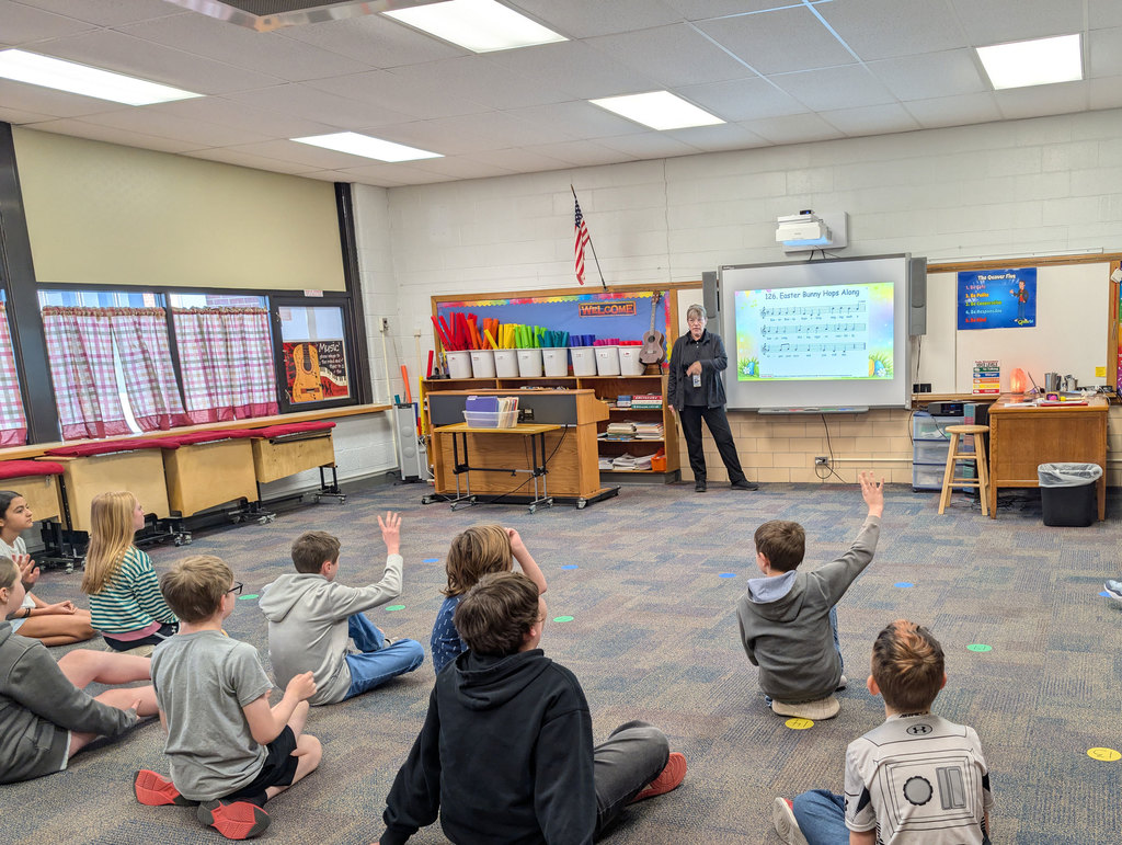 Elementary music students reviewing parts of sheet music.