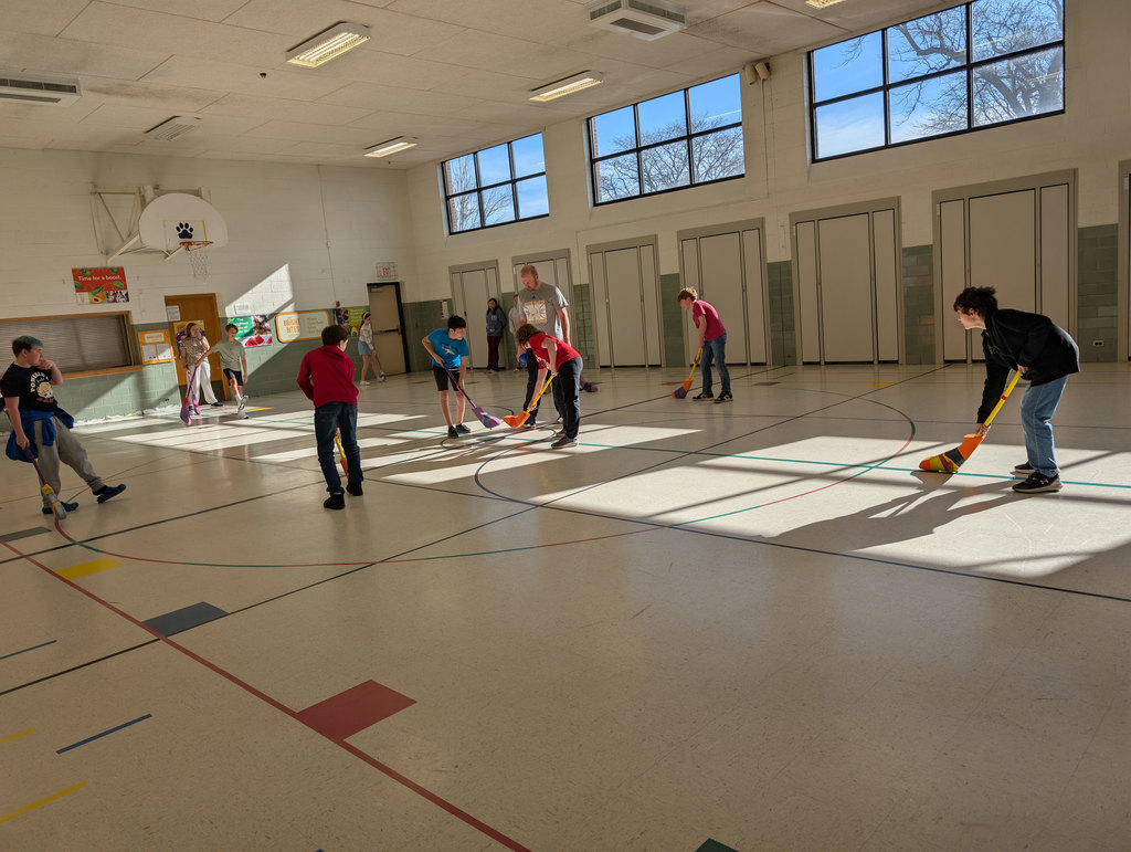 Elementary students playing hockey in PE.