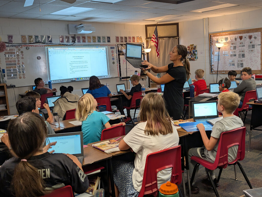 Students working with teacher on computers