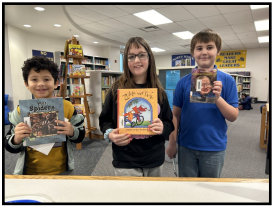 Three students holding up Books 
