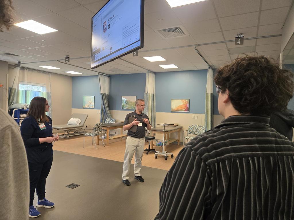 students standing listening to a guy instruct with medical beds in the background.