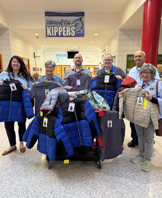 adults standing around their donation of new winter coats