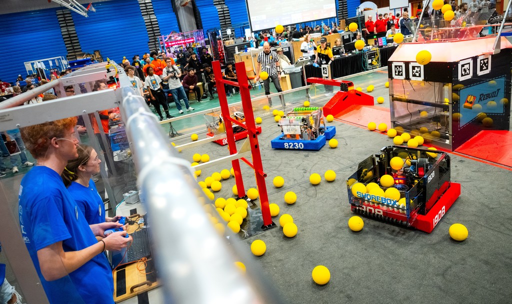 Robotics students at competition with robot picking up balls