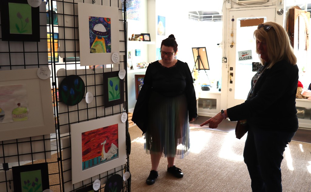 adutls browsing student artwork in an art gallery