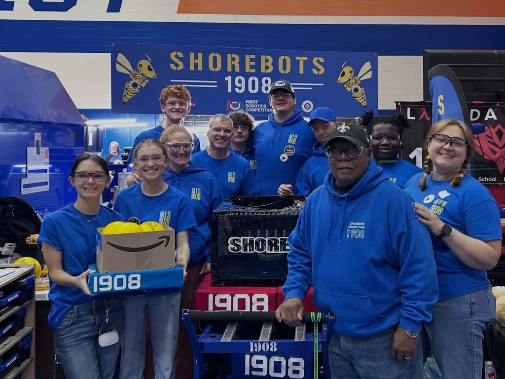 group photo of the ShoreBots posing with their robot after placing 6th in the district championship and heading to the world finals. Everyone is happy and smiling.
