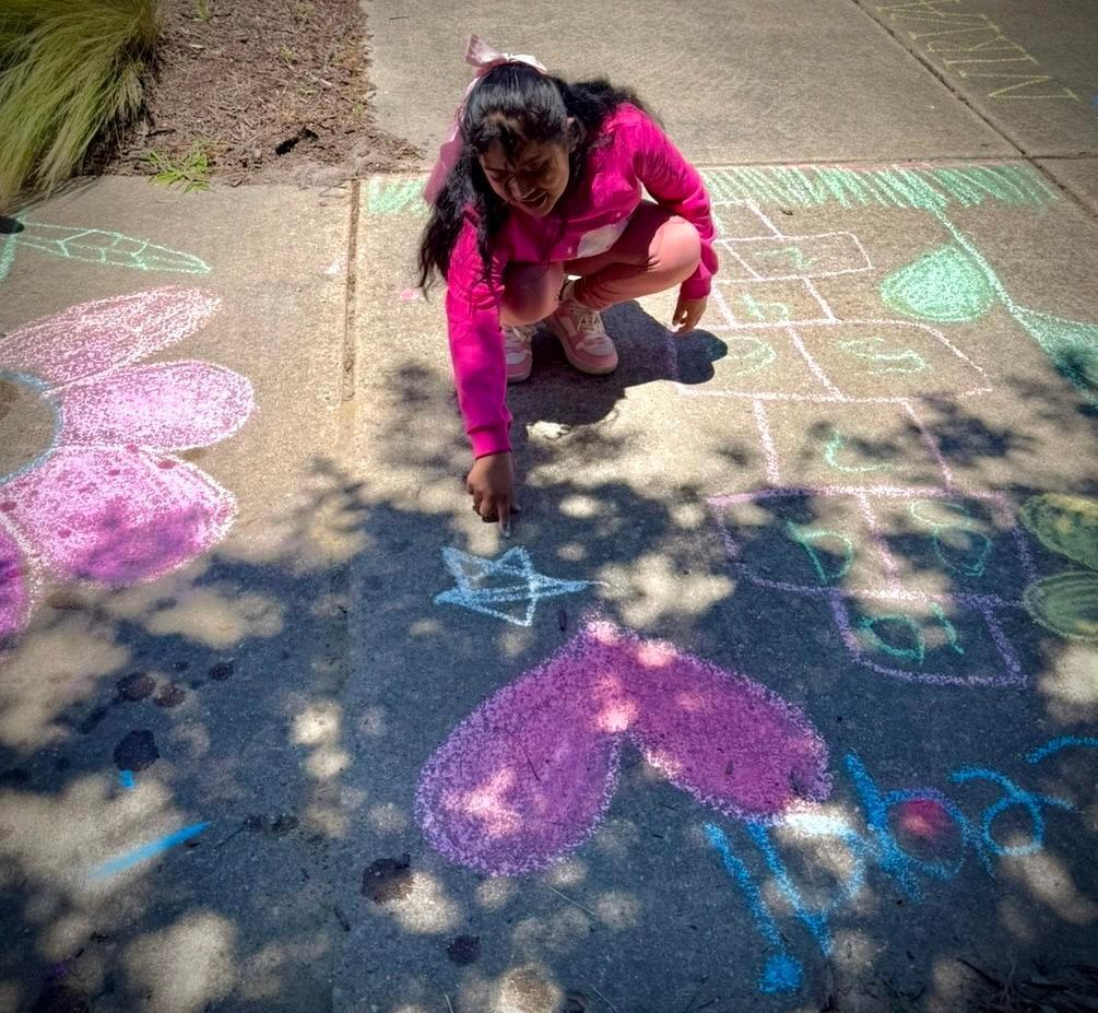young girl creates images on sidewalk with chalk