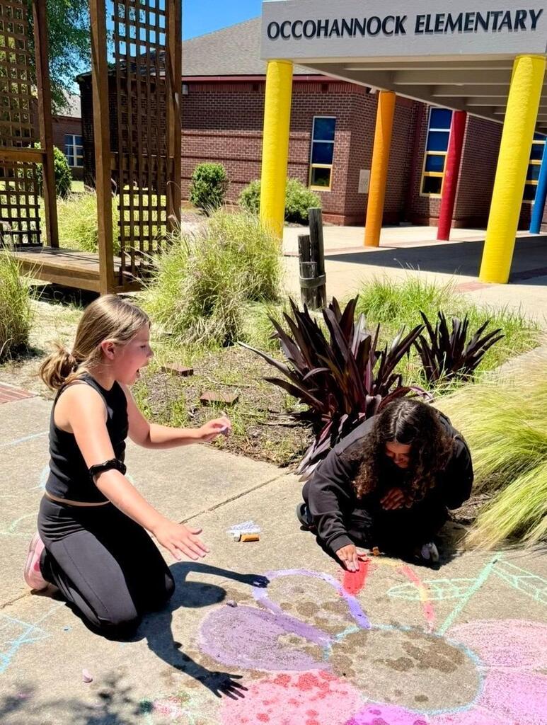 young girls creates images on sidewalk with chalk