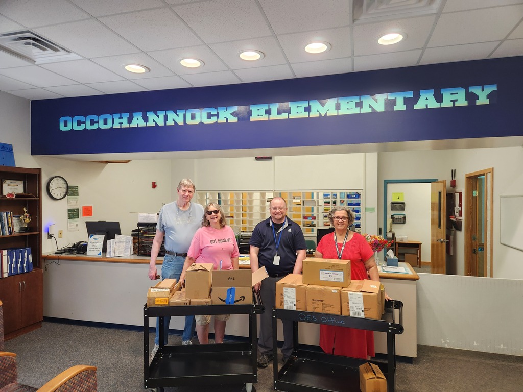 four adults post with donated school supplies in boxes.