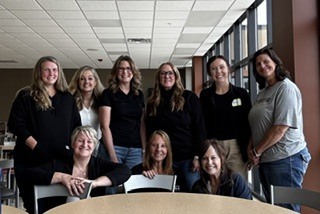 nine females in a group around a table, 3 women are kneeling in the front