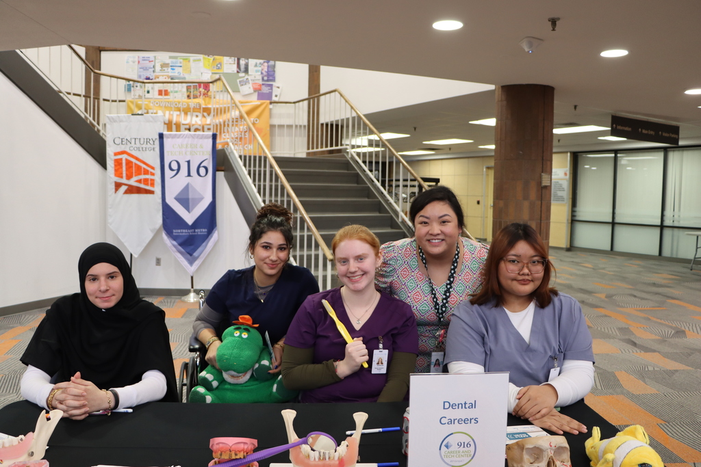 Staff and students at a booth smiling.