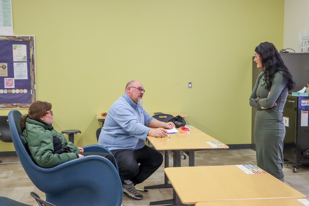 Image of a presenter talking with parent and student about their presentation.