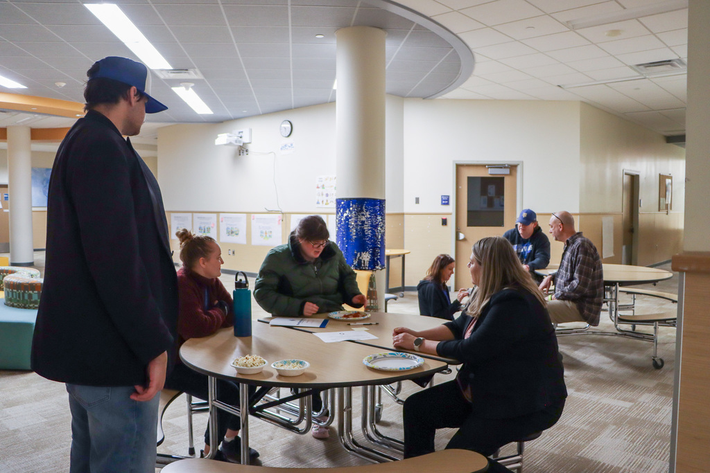 Students and staff sitting at a lunch table eating.