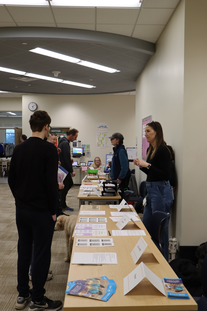 Image of a row of desks with staff, students, and families talking to each other.