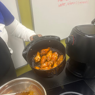 Image of a person showing chicken wings that were cooked in an air fryer.