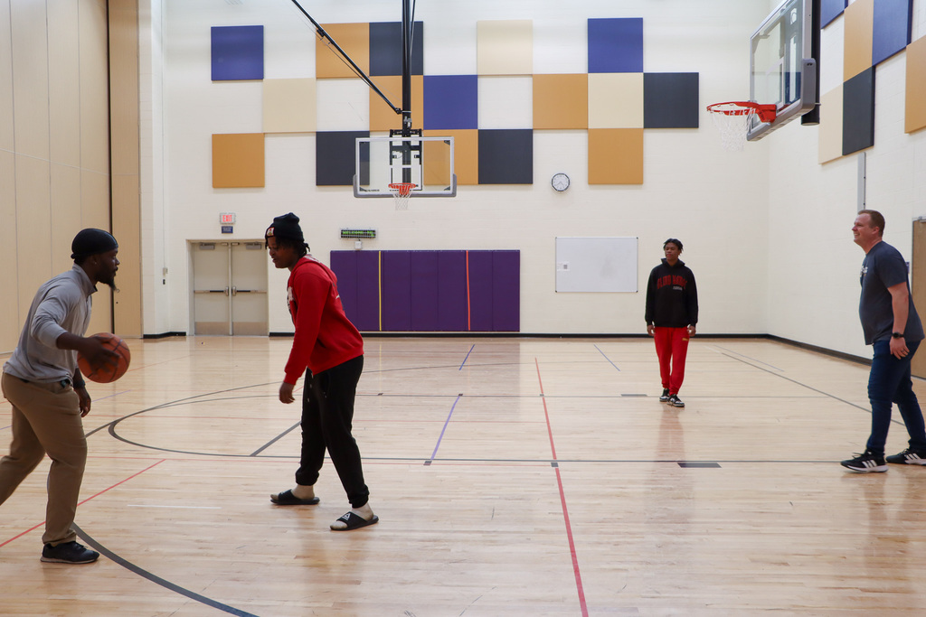 Image of students and staff playing basketball in a gym.
