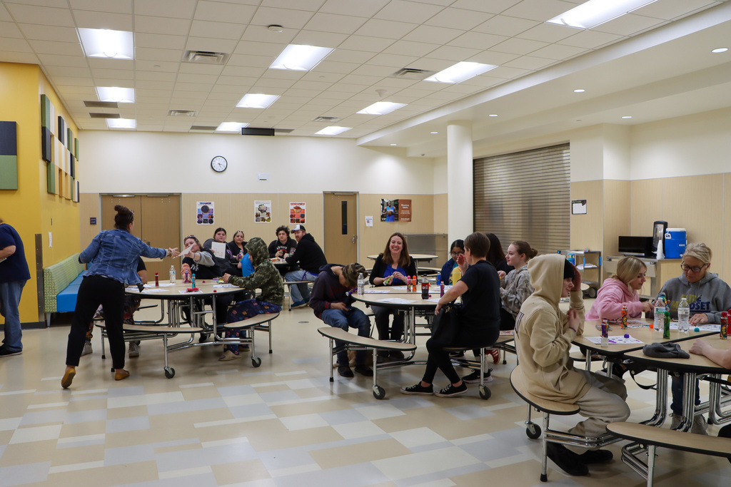 Image of students, staff, families, and caregivers sitting at tables in the lunchroom while playing bingo.