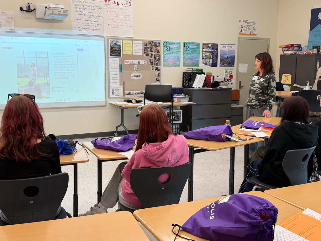 Students in a classroom listening to a career professional talk about their career. 