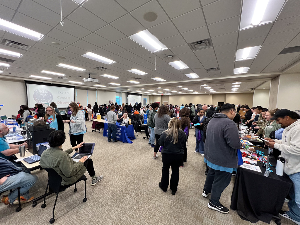 Students and staff walking around talking to career professionals and college vendors in a conference room.