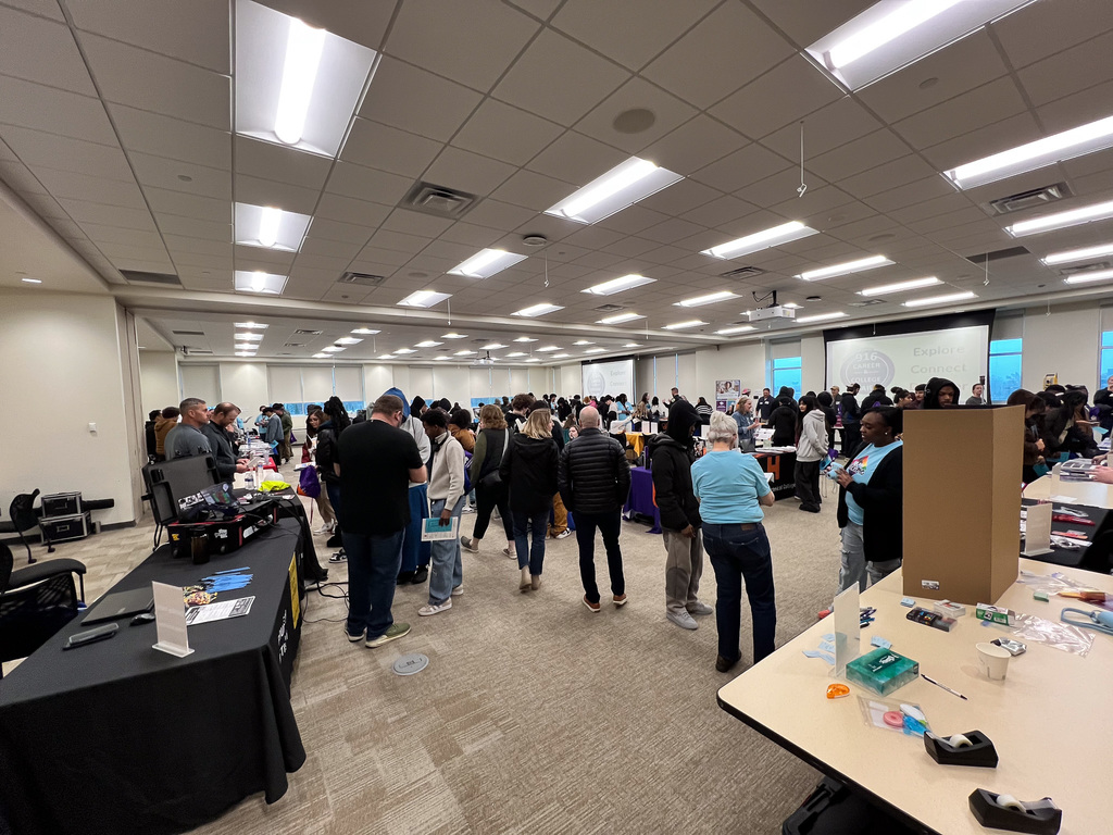 Students and staff walking around talking to career professionals and college vendors in a conference room.