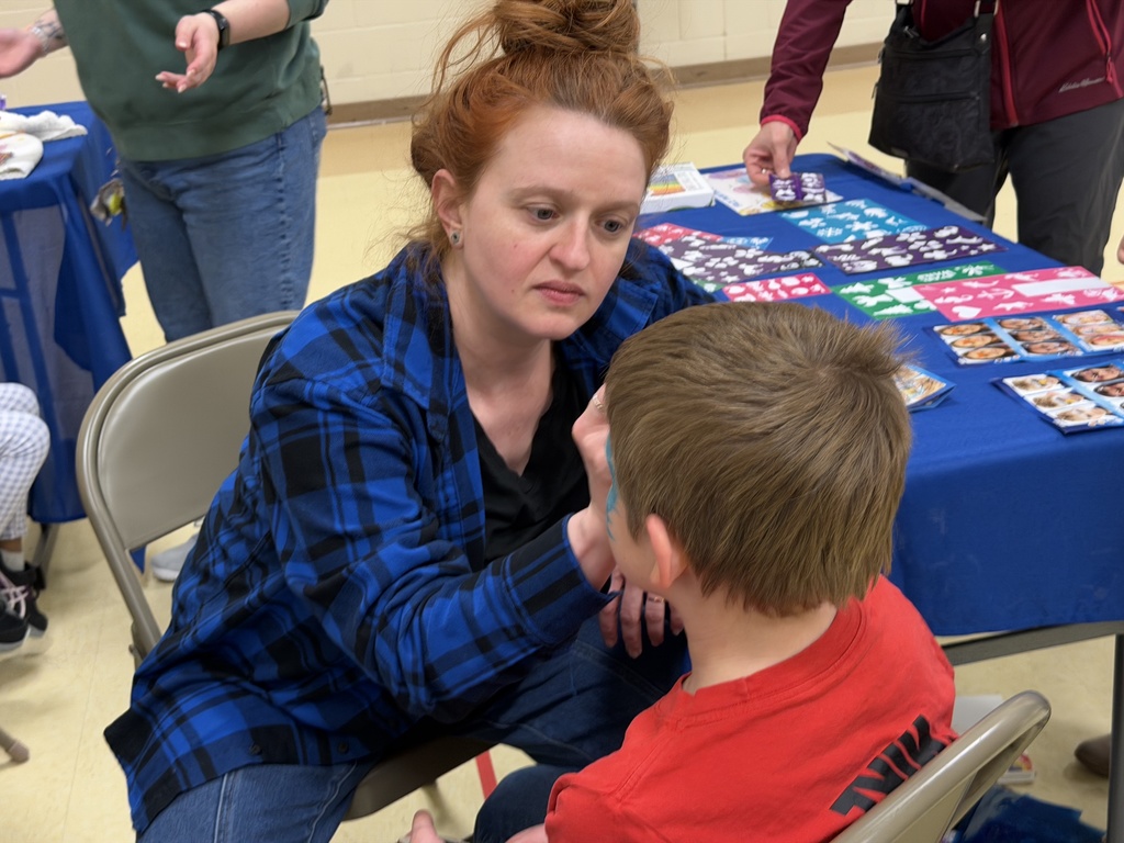 Staff face painting a student. 