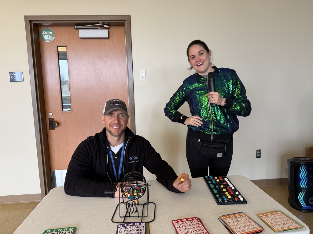 Two staff smiling as they call out bingo numbers. 