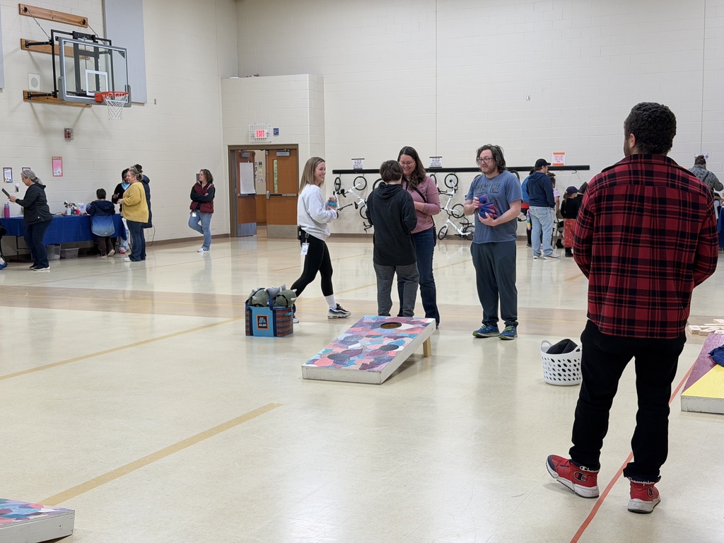 Staff, students, and families interacting and playing games in a gym.
