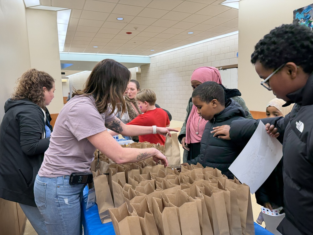 Staff handing out paper bags of goods to students and families. 
