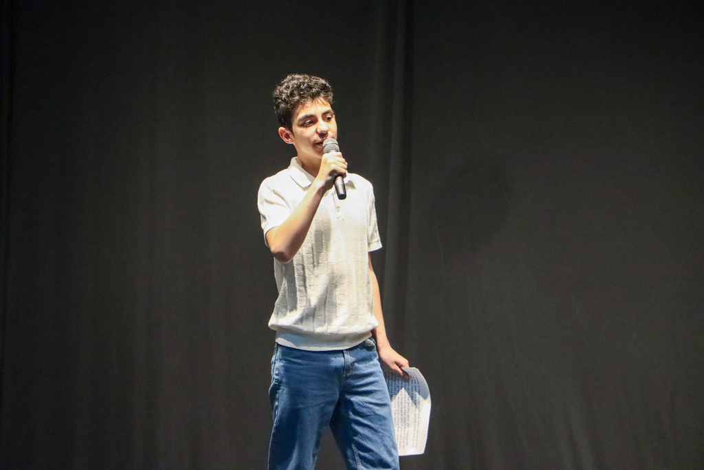 Student with microphone in hand and telling jokes to audience.
