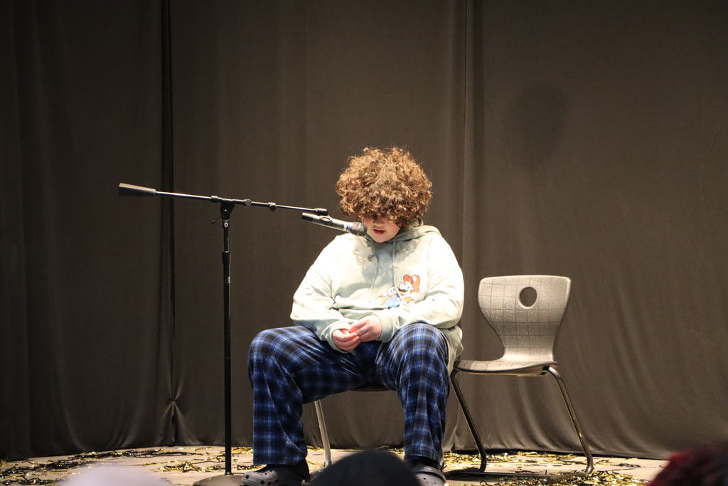 Student sitting in a chair and singing. 